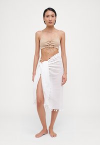Beige stripete crop top med frontknute og hvit omslagskjørt med teksturert finish og duskdetaljer i kanten.