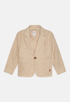 Blazer en lin beige avec fermeture à un bouton, revers crantés, deux poches avant et un petit détail de logo brodé.