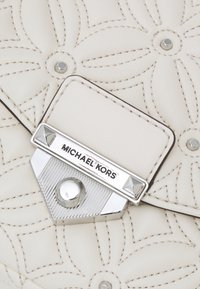 Borsa a tracolla in pelle crema con ricami floreali e chiusura in argento incisa con il logo Michael Kors.