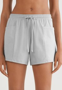 Lichtgrijze shorts van zacht materiaal, met een elastische tailleband met trekkoord, twee zijzakken en een ontspannen pasvorm.