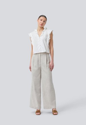 Hvit rynket bluse med V-hals og knapper, kombinert med lysegrå vide bukser og brune sandaler. Enkel og strukturert design.