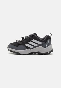 Black and grey outdoor shoes with a mesh upper, rubber sole, and elastic cord lacing. Features three white stripes on the side and textured accents.