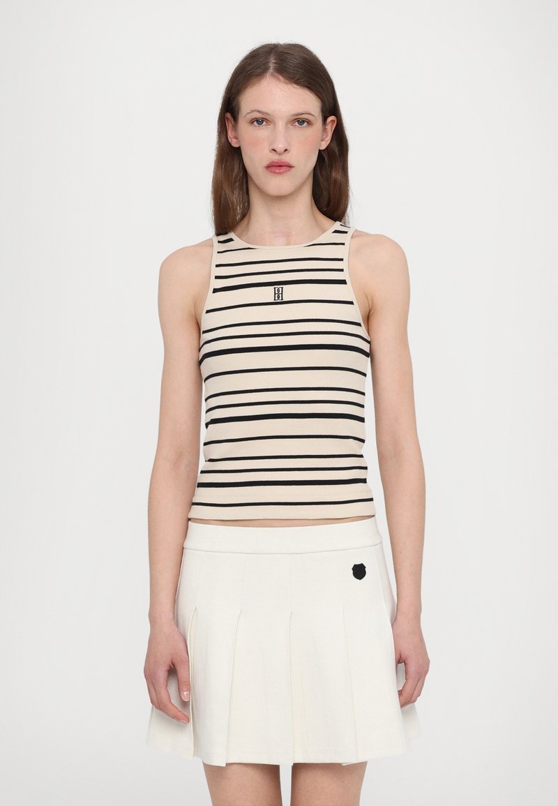 Striped tank top in beige and black, ribbed texture, with a fitted design and logo at center; paired with a pleated white skirt featuring a black accent.
