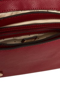 Portefeuille en cuir rouge texturé avec plusieurs compartiments, une poche zippée et un intérieur en tissu beige avec un motif subtil.