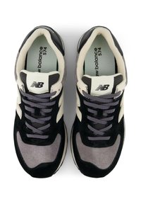 Sneaker in suede e mesh neri e grigi con un accento crema, dotati di lacci rotondi, linguetta imbottita e un logo sul lato e sulla linguetta.