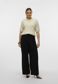 Cremefarvet ribstrikket sweater med korte ærmer, parret med højtaljede sorte vide bukser og bordeauxfarvede spidse hæle.