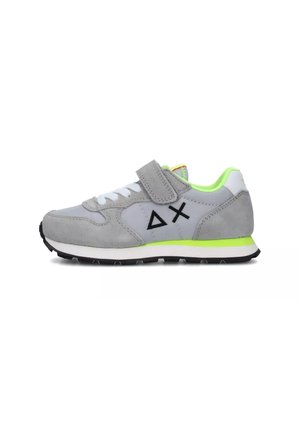Scarpa sportiva grigia con cinturino in velcro, lacci bianchi, dettagli verde neon e suola nera. Presenta materiali scamosciati e sintetici con logo geometrico.