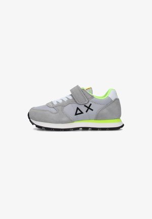 Scarpa sportiva grigia con cinturino in velcro, lacci bianchi, dettagli verde neon e suola nera. Presenta materiali scamosciati e sintetici con logo geometrico.