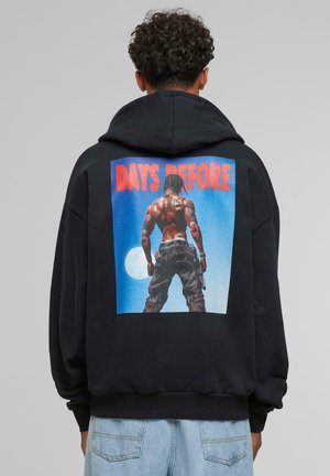 Black hoodie featuring a large graphic on the back showing a muscular figure against a blue background with “DAYS BEFORE” in bold red letters.
