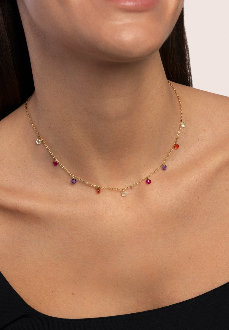Collana in oro con più pietre preziose colorate (rosse, viola, trasparenti) sospese a intervalli, che accentuano il collo.