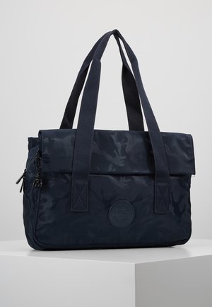 Torba typu tote w ciemnoniebieskim kamuflażu z podwójnymi długimi materiałowymi uchwytami, zapinana na zamek boczną kieszenią oraz okrągłą naszywką marki z przodu.