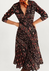 Robe noire avec un décolleté en V, des manches trois-quarts et une jupe évasée. Présente un motif floral paisley dans des tons rouges et dorés.