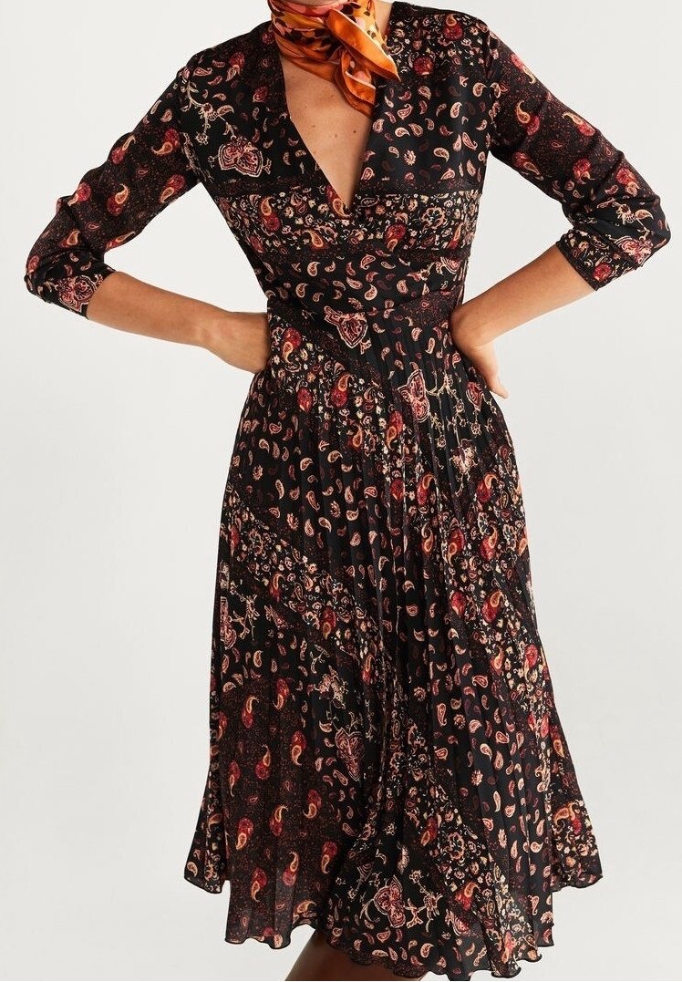 Robe noire avec un décolleté en V, des manches trois-quarts et une jupe évasée. Présente un motif floral paisley dans des tons rouges et dorés.