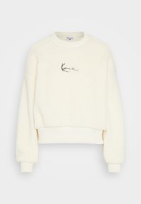 Felpa cropped di colore crema e morbida, con polsini e orlo a coste. Presenta un semplice logo nero con firma sul fronte, realizzato in materiale soffice.