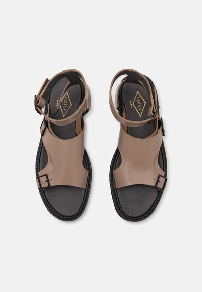 Brown and black sandals with a wide strap design, textured soles, adjustable ankle straps, and a buckle detail. Durable materials used.