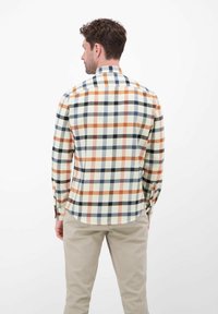 Wielokolorowa koszula w kratę w odcieniach pomarańczowym, granatowym i kremowym; z długimi rękawami, mankietami na guziki oraz zaokrąglonym dołem; wykonana z miękkiego materiału.
