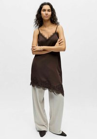 Camisole en satin marron avec bordure en dentelle à l'ourlet, associée à un pantalon large gris clair. Design simple avec bretelles spaghetti réglables.