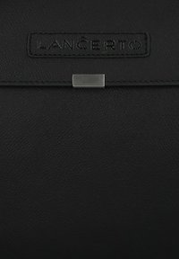 Czarna skórzana torba z teksturowaną powierzchnią, naszywką z logo oraz metalowym zapięciem. Kompaktowy i prostokątny design.