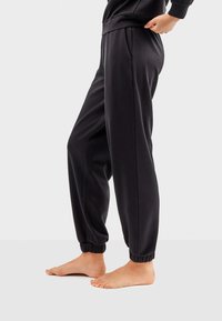 Sorte sweatpants med elastisk talje og manchetter, der har en glat tekstur og sidelommer, stylet til en afslappet pasform.