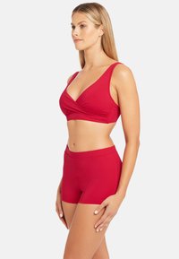 Rotes Bade-Set mit einem Wickeloberteil mit breiten Trägern und einer passenden hochgeschnittenen Shorts. Glatte Textur und figurbetontes Design.