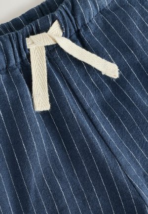 Tengerészkék csíkozott anyag vékony fehér vonalakkal, rugalmas derékrésszel és kontrasztos elefántcsont színű pamut zsinórral.