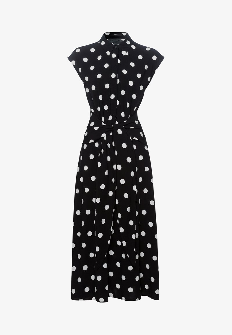 Robe midi noire sans manches à pois blancs, avec col, boutons sur le devant et ceinture nouée à la taille.