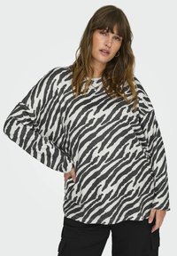 Maglietta a maniche lunghe con un motivo a strisce zebrate in bianco e nero, scollatura rotonda e vestibilità comoda. Realizzata in tessuto misto cotone con una consistenza morbida.