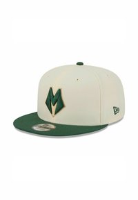 Cremefarbener Baseballcap mit grünem, flachem Schirm, mit einem auffälligen grünen "M"-Logo vorne und einem kleinen Markenlogo an der Seite.