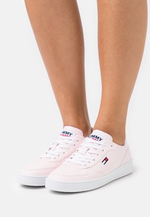 Rosa syntetiska sneakers med vita gummisulor och snören. Har en logotyp på tungan och en liten accent nära hälen.
