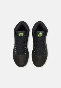Scarpe sportive nere con tomaia in rete testurizzata, dettagli verdi sui lacci e punta decorata. Design della linguetta e del colletto imbottito.