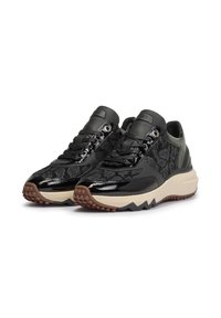 Schwarze Sneakers aus lackiertem Leder und strukturiertem Stoff, mit einer beigefarbenen Zwischensohle und einer braunen Gummisohle mit Zickzackmuster.