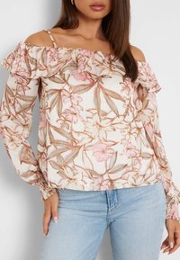 Cvjetna bluzica s otkrivenim ramenima i volanima, izrađena od lagane tkanine u krem, ružičastim i zelenim tonovima. Dugi rukavi s elastikama na manžetama.