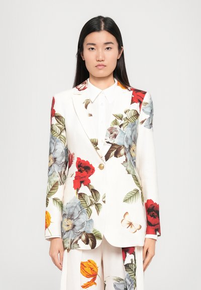 Blazer floral blanc, orné de fleurs rouges et bleues, de feuilles vertes, et d'un bouton doré. Design ajusté avec poches avant et texture subtile.