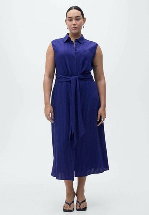Sleeveless, button-down dress in deep blue with a tied waist. Features a ribbed texture and midi length, paired with black sandals.