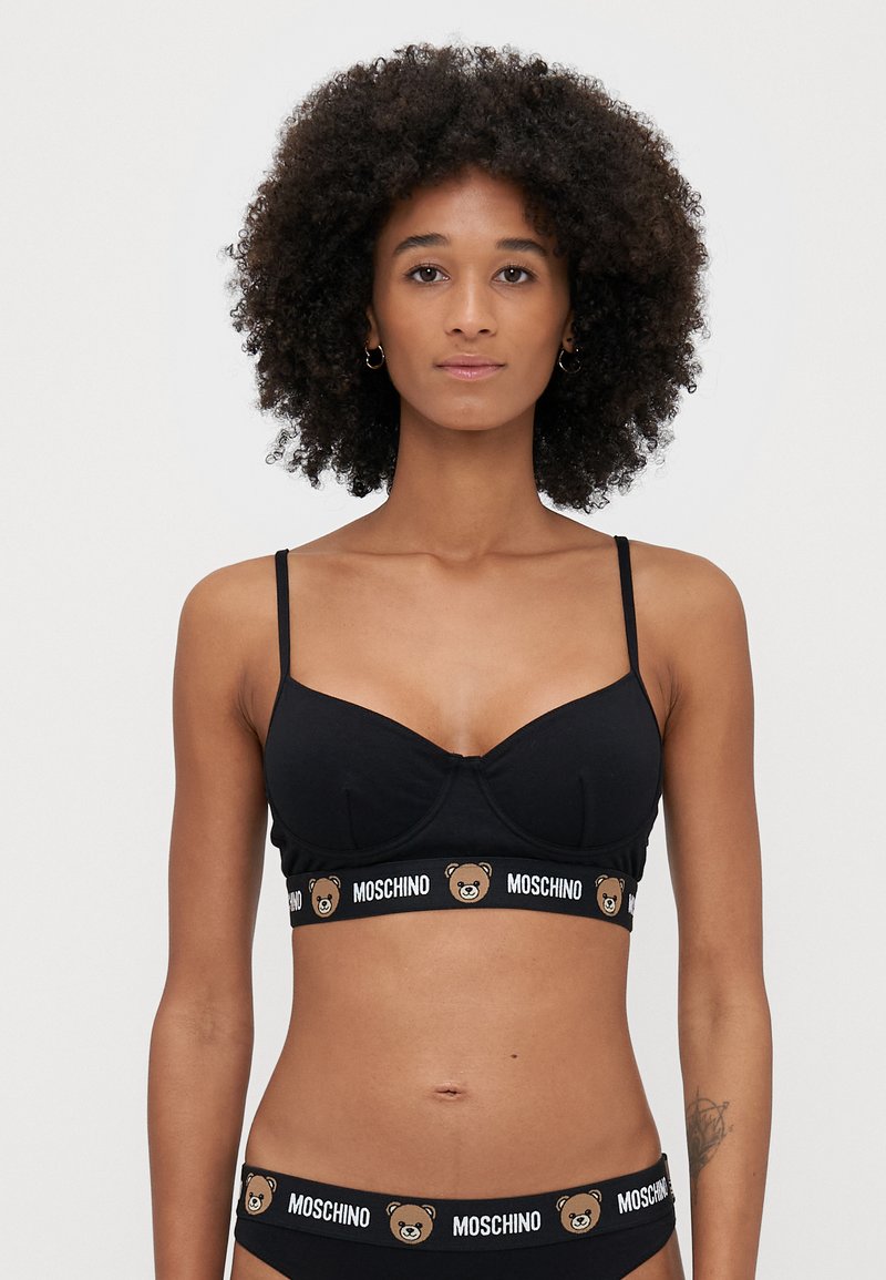 Čierny bralet s tenkými ramienkami, tvarovanými pohárikmi, s logom medveďa a pásom "MOSCHINO". Hladká textúra, voľný dizajn.