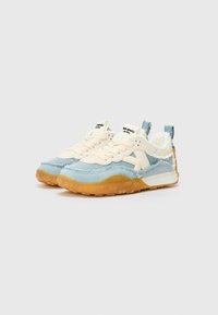 Des baskets avec un schéma de couleurs bleu clair et crème, fabriquées en denim, avec des accents texturés et une semelle en caoutchouc gomme avec un motif strié.