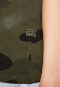 Zelené maskáčové tričko vyrobené z bavlny, s logem G-Star RAW na nášivce. Tkanina má jemnou texturu s oblámi v různých odstínech.