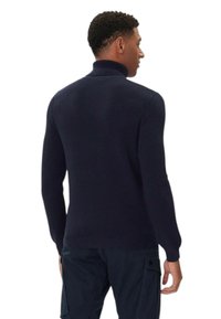 Maglione lavorato a maglia blu navy con collo alto, materiale strutturato e polsini e orlo a coste, visto da dietro.