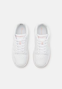 Zapatillas blancas con una textura de cuero suave, con un puntera perforada, cordones blancos y un sutil acento rosa en el lateral.