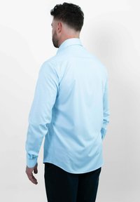 Lichtblauw langemouw shirt met een gebogen zoom, voorzien van een klassieke kraag en manchetten met één knoop, gemaakt van een gladde stof.