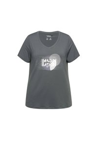 Grijze V-hals T-shirt van zacht materiaal, met een witte opdruk waarop het woord "IMAGINATION" gedeeltelijk is verstopt door patronen.