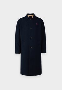 Cappotto di lana navy con colletto classico, chiusura a cinque bottoni, due tasche laterali e una piccola etichetta con logo vicino al petto.