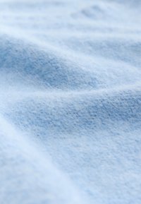 Light blue fabric with a soft, textured surface, displaying a gentle wave pattern and fine, fuzzy fibers throughout.