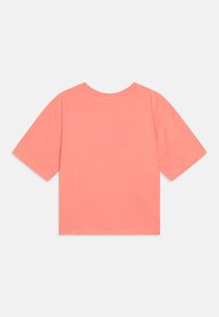 T-shirt corail à manches courtes avec un col rond, fabriqué en tissu doux, offrant une coupe décontractée et sans graphiques ni motifs visibles.