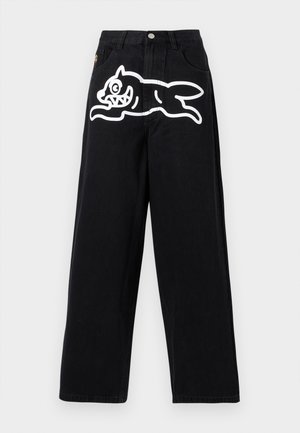 Jean noir à jambes larges avec taille haute et un graphisme blanc d'un chien de dessin animé joueur sautant sur la partie supérieure de la cuisse avant.