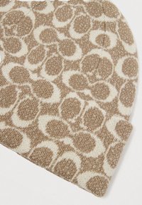 Caciula cu un model de leopard în nuanțe de bej și crem, având o textură moale și un sclipici subtil. Material tricotat cu vârf rotunjit.