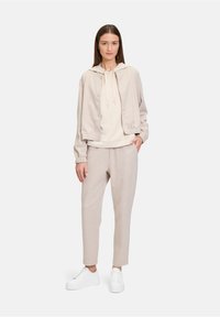 Beige sweatshirt en bijpassende joggers, gemêleerd materiaal, elastische manchetten, met capuchon, aangevuld met witte sneakers.