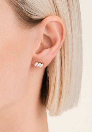 Tre orecchini a forma di rettangolo in cristallo, montati su metallo color oro, caratterizzati da un design elegante e moderno.