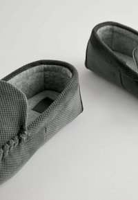 Chaussons gris avec un extérieur texturé et une doublure en tissu doux, présentant un bout fermé, un profil bas et un design minimaliste.