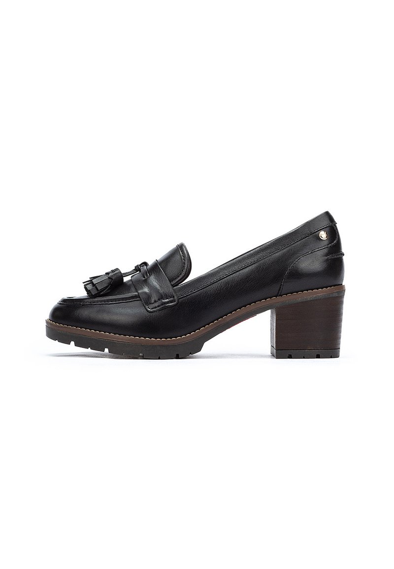 Mocassino in pelle nera con tacco basso a blocco, nappine decorative e suola texturizzata. Finitura liscia con un dettaglio di cuciture chiare a contrasto.